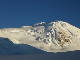 Рис. 4.44. Вид на вершину 5921 с ледника Федченко. Ледоруб установлен на скале в средней части гребня. Фото на юг. Для спуска на ледник Федченко нужно траверсировать весь гребень слева от вершины 5921. Начало спуска с гребня на ледник Федченко находится за пределами левой границы кадра..