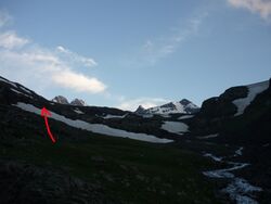 Фото 9. Вид вверх после преодоления первого пояса скал. Стрелкой обозначен наш примерный путь, возможно, правильный путь лежит правее.